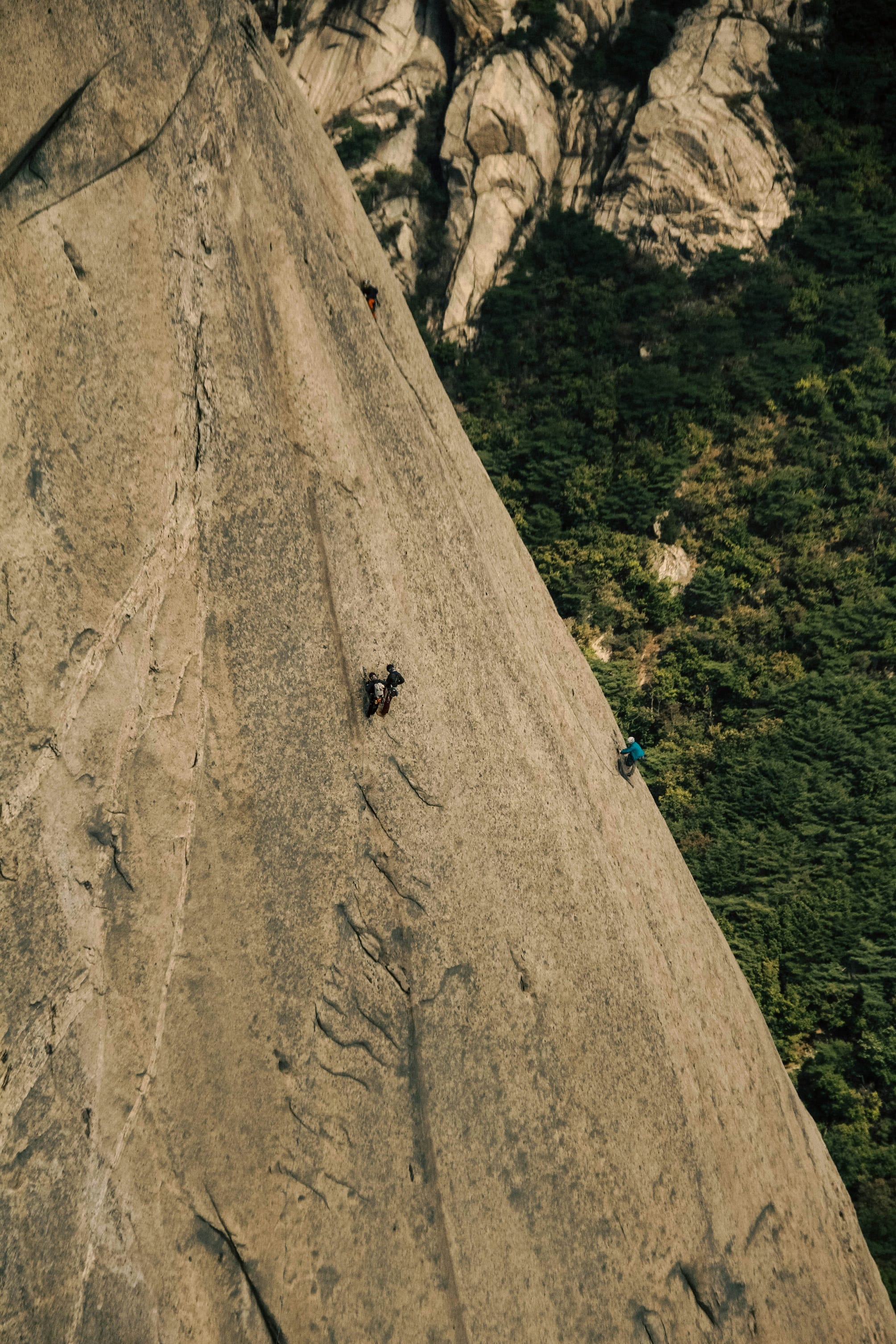 A man climbing up the side of a mountain in Bukhansan, South Korea.