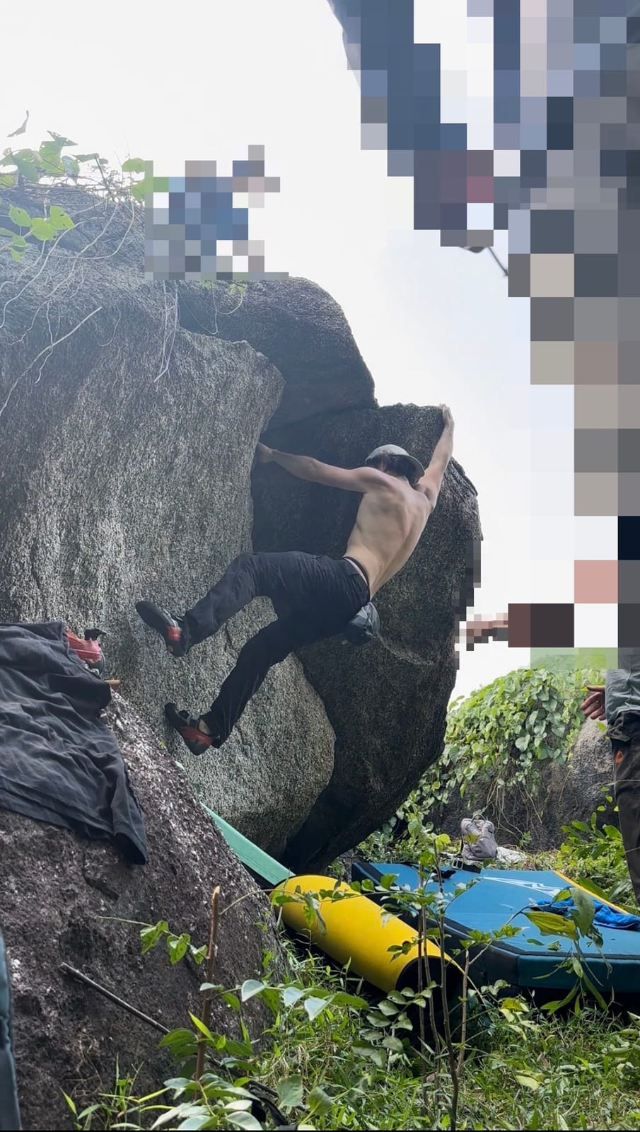 Climber on an overhanging granite boulder with crash pads in the Ba Na Hills, Da Nang