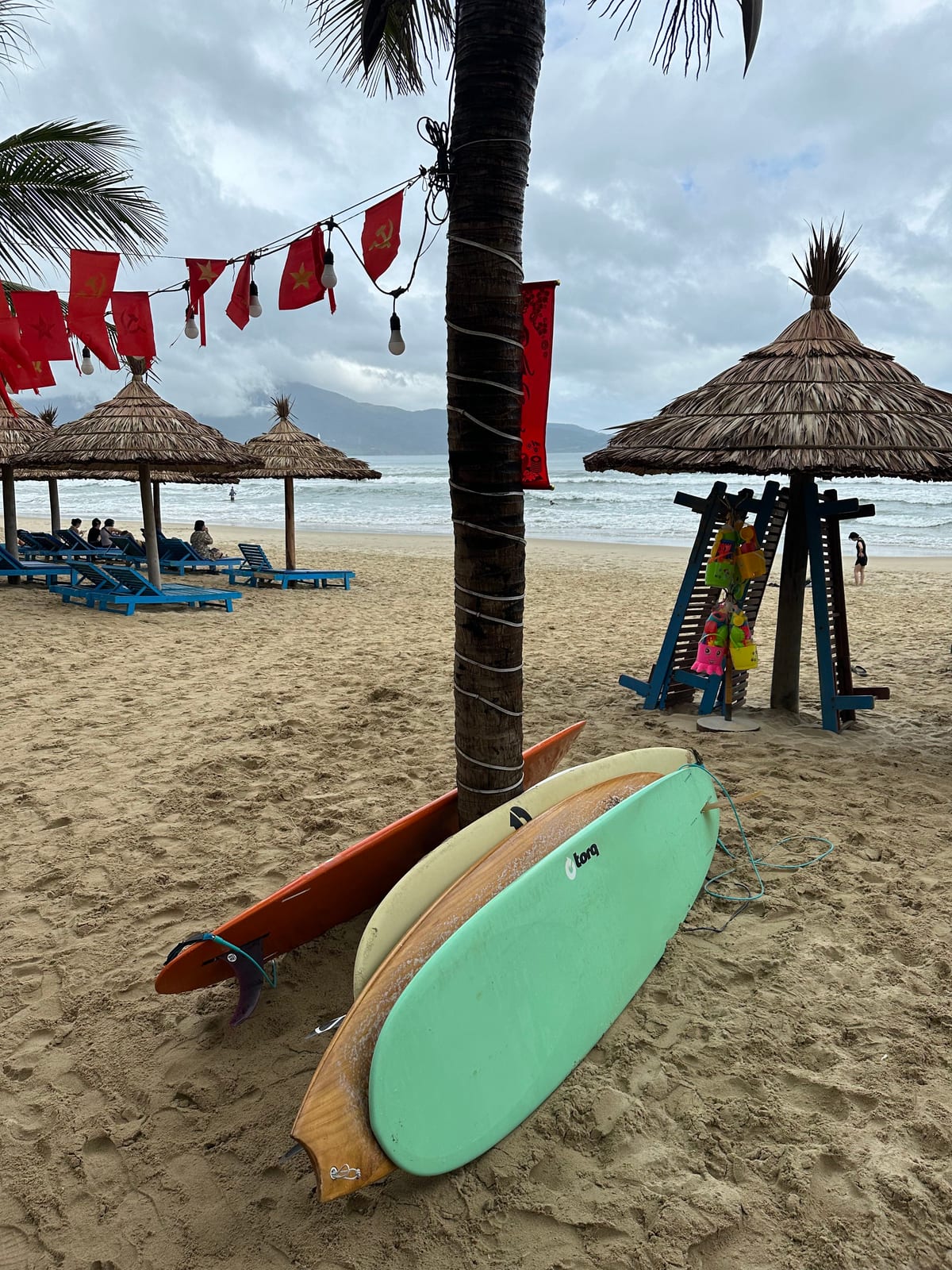 Surfboards for rent under a palm tree on My Khe beach, Da Nang