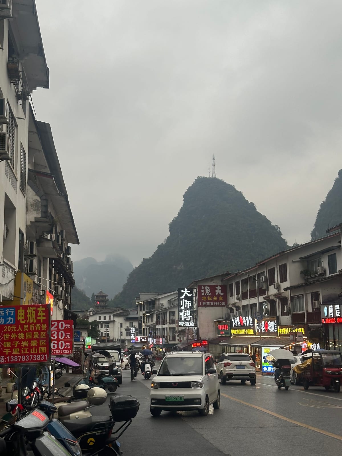 Yangshuo town street with a karst tower in the cloud at dusk, Guangxi, China