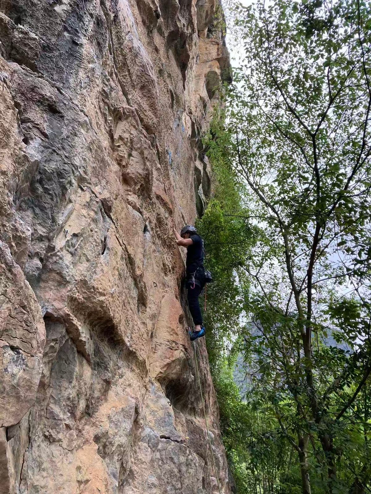 Climber high on a 6b route on the East Wall at Twin Gates, Yangshuo
