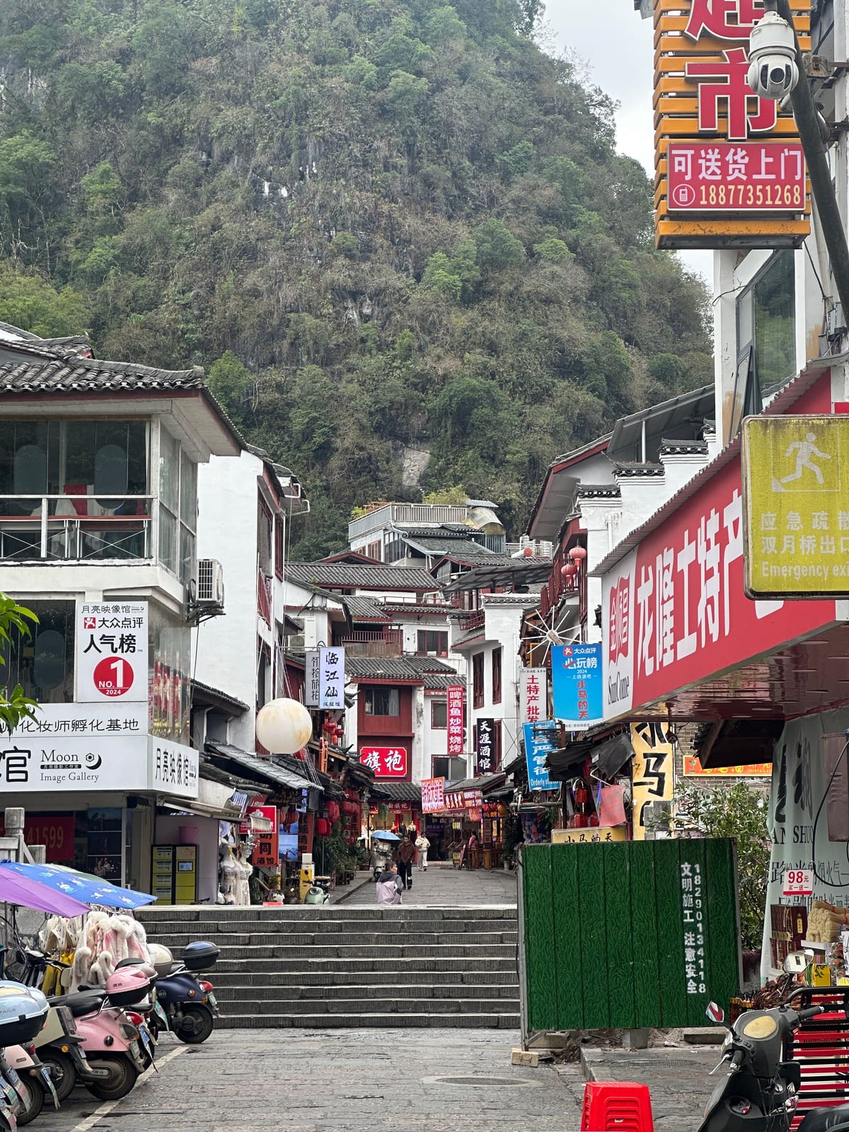 West Street in Yangshuo town with shops and karst hills behind