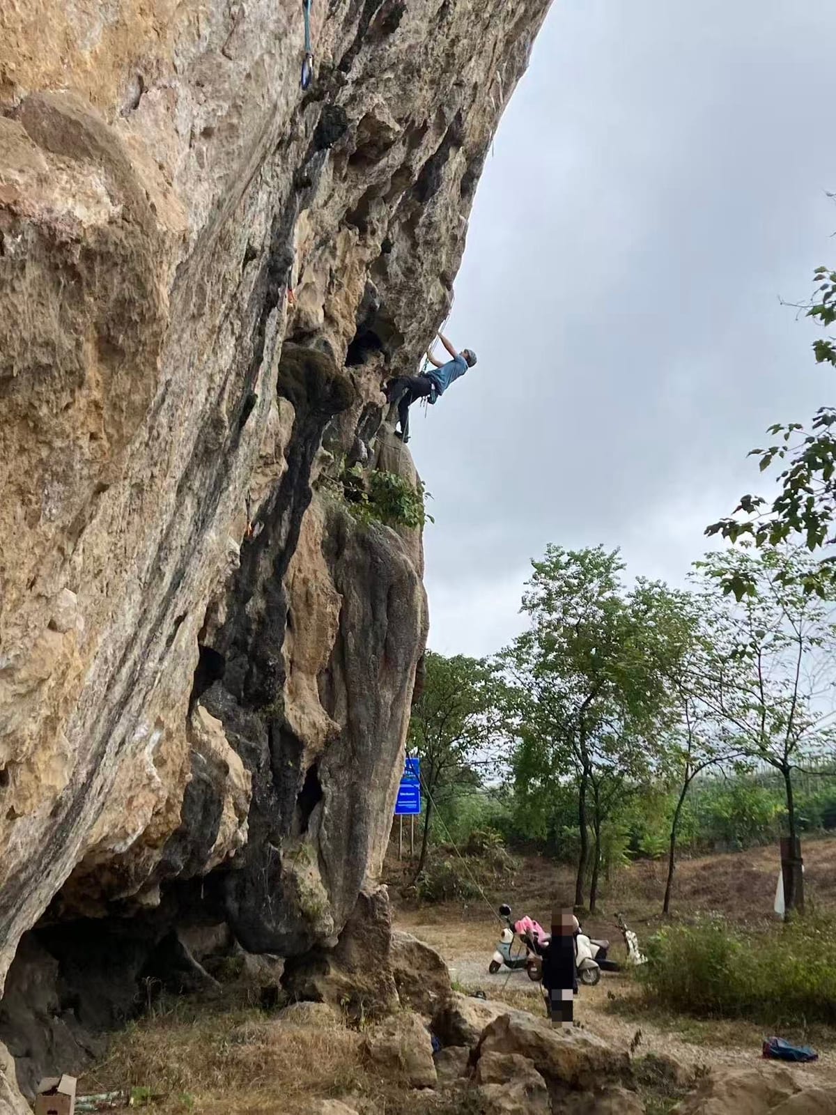 Overhanging limestone with a climber high on a route at White Mountain, Yangshuo