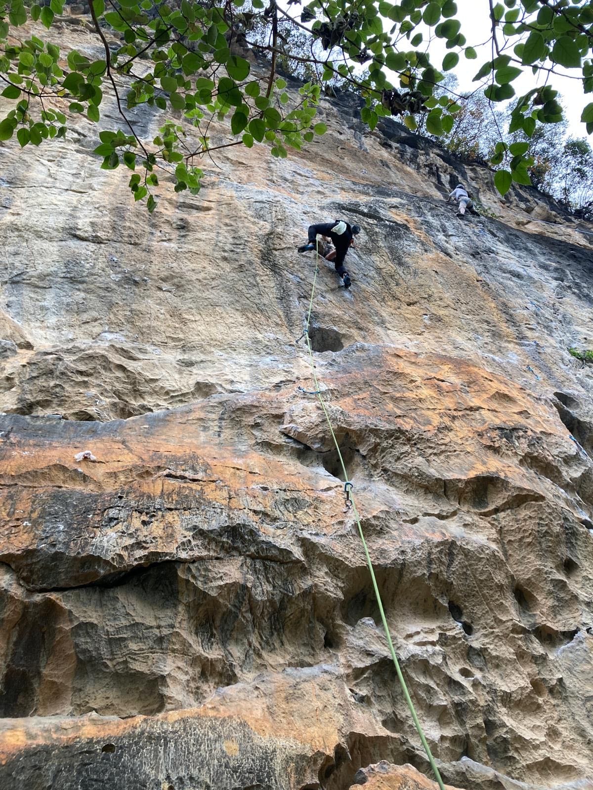 Climber traversing under a roof band at White Mountain crag, Yangshuo, China