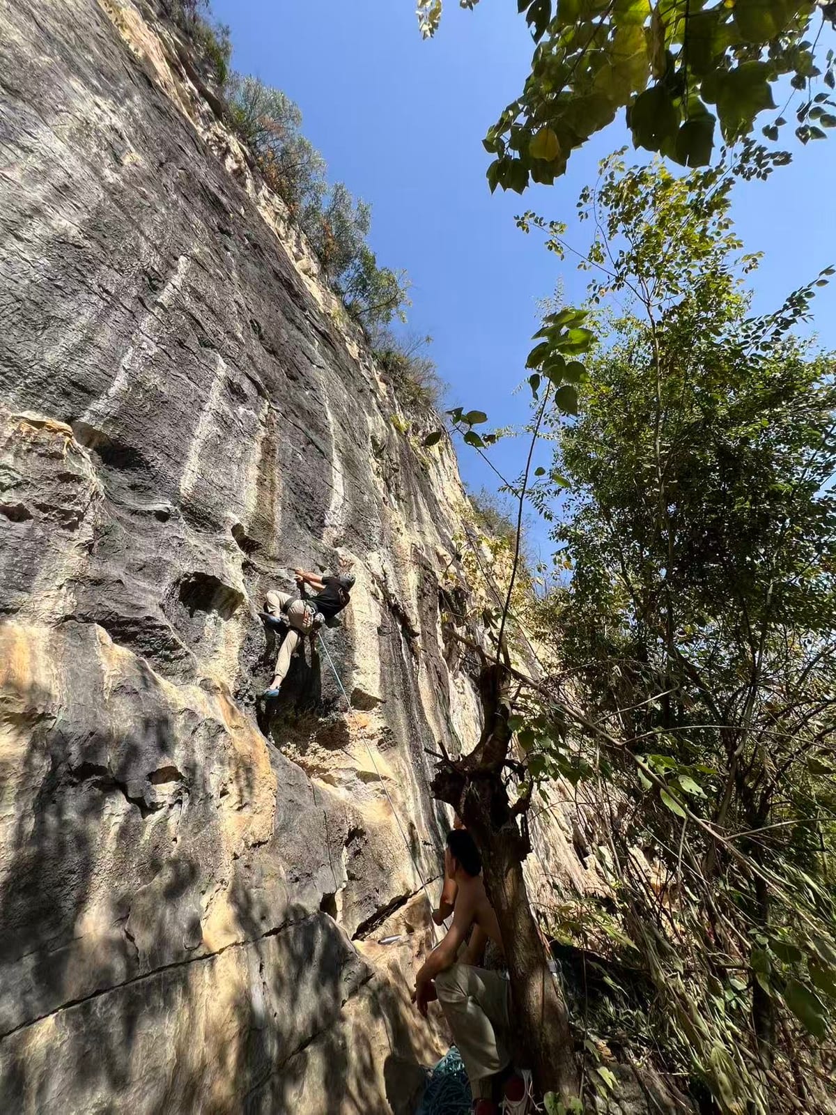 Wine Bottle crag in Yangshuo with climbers on the vertical grey limestone wall